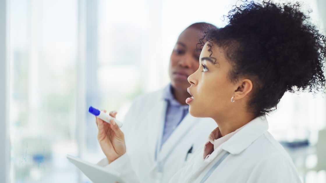 female scientist writing on a whiteboard