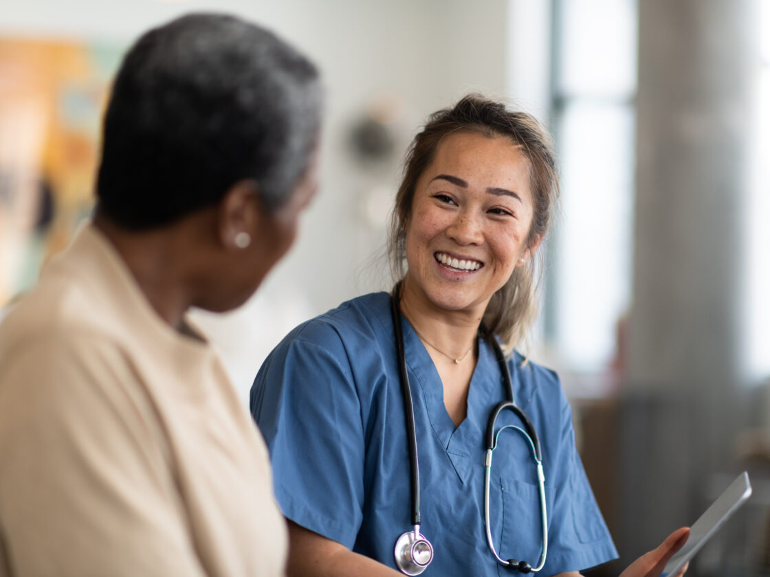 doctor is talking to a woman while holding a tablet computer