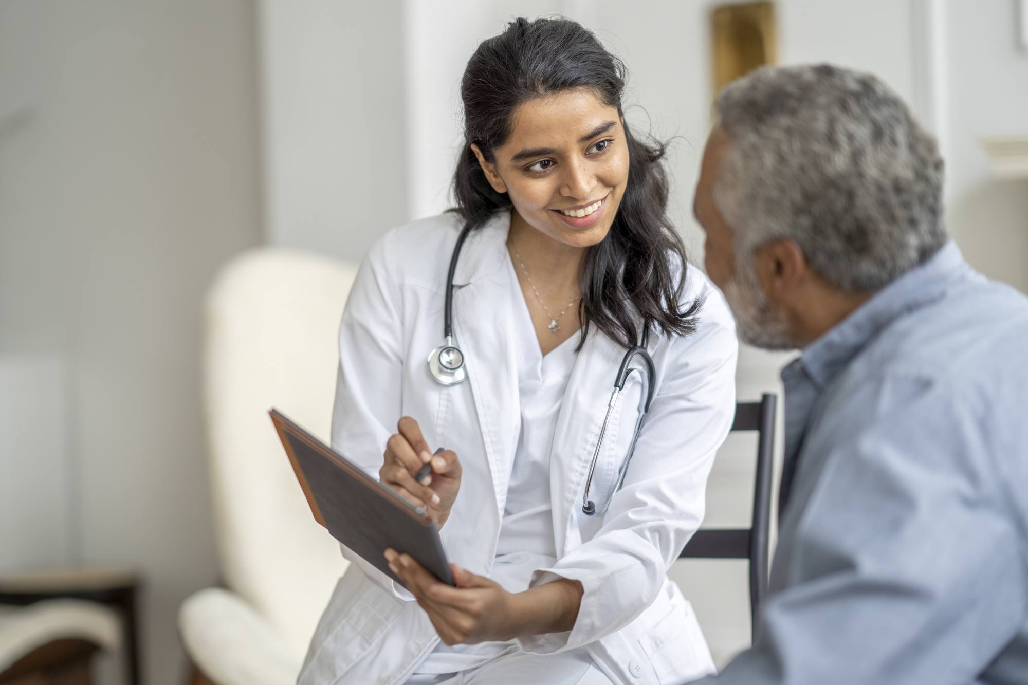 Young female doctor sits with a senior patient