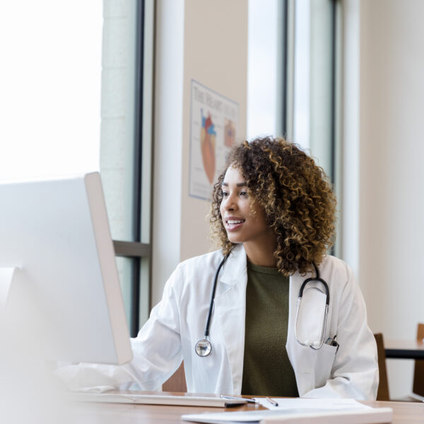 doctor reviews patient records on desktop PC