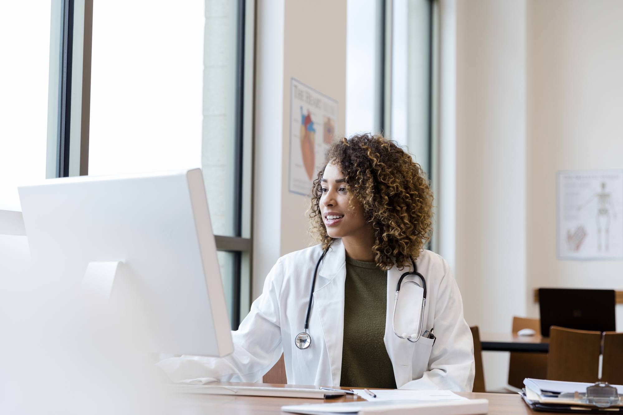 doctor reviews patient records on desktop PC