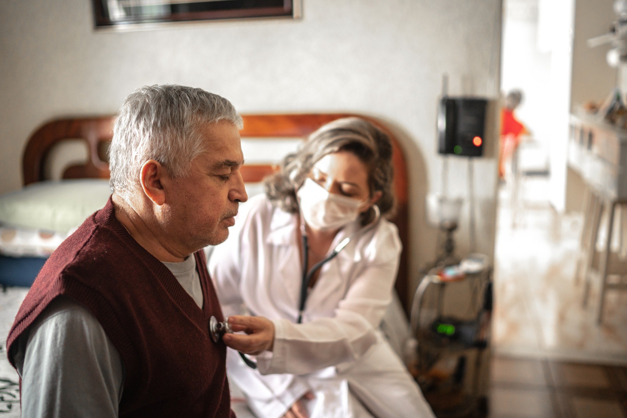 nurse listening to heartbeat of senior man