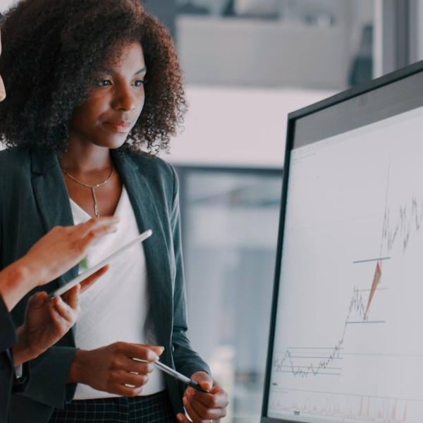 two young businesswomen using an interactive whiteboard to analyse data