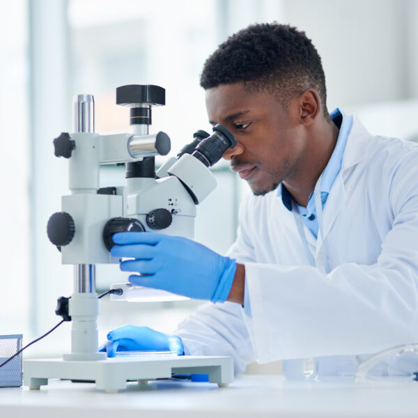 young male scientist looking at test samples through a microscope