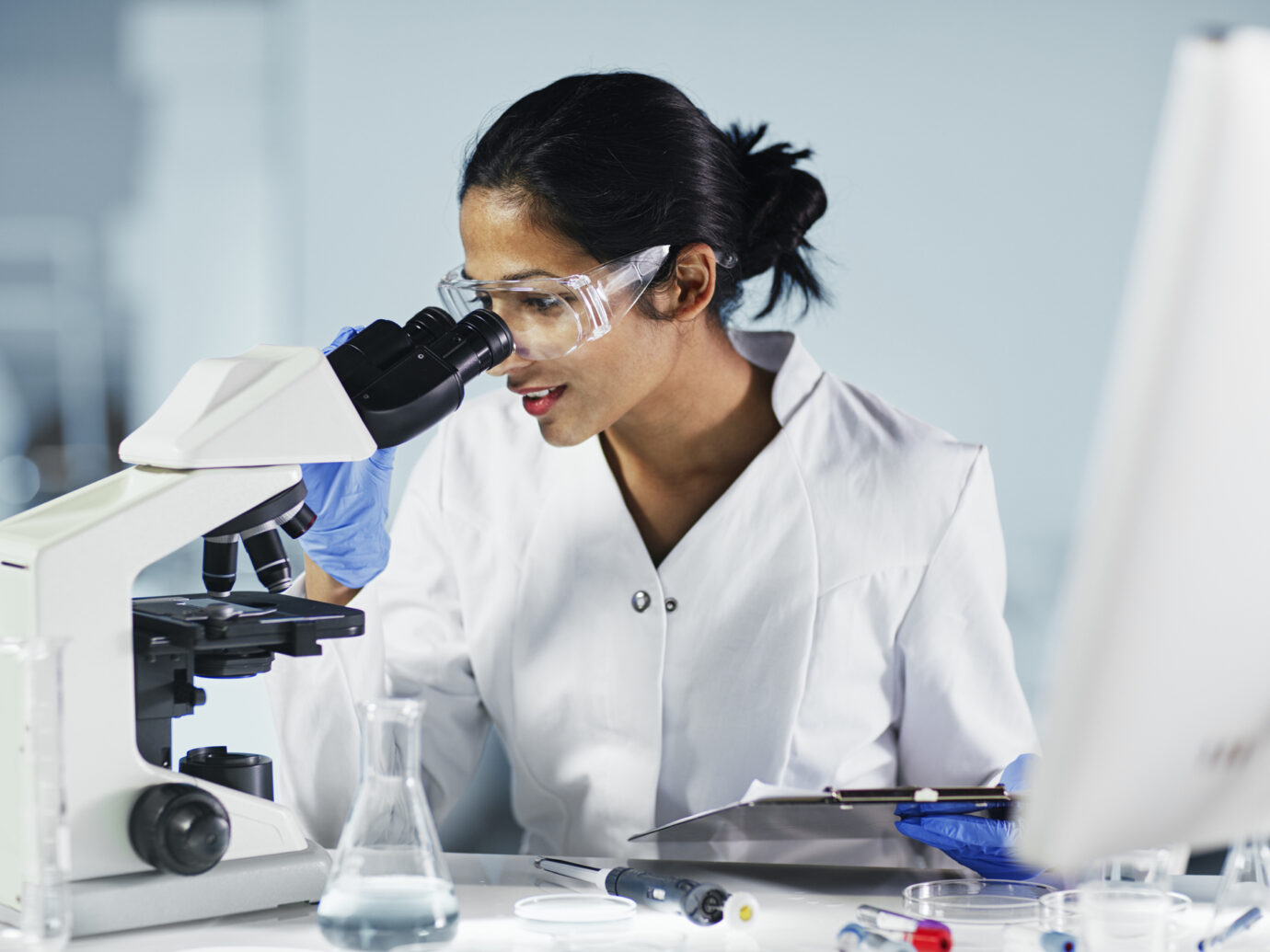 female medical researcher using microscope