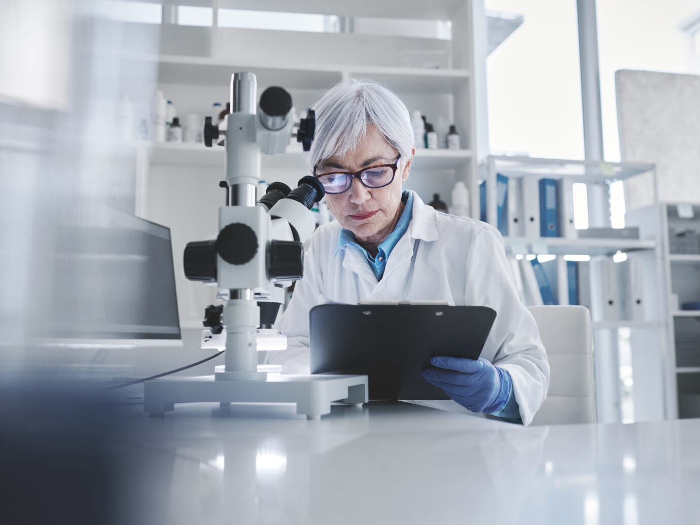 mature scientist writing on clipboard