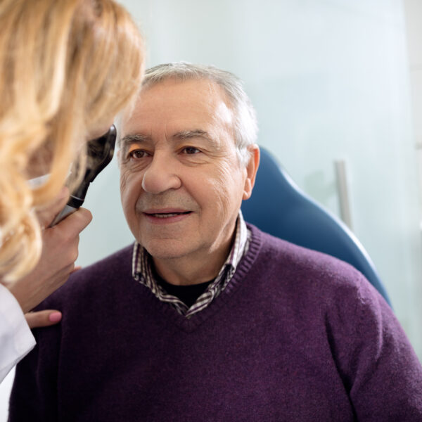 Senior looks in instrument for checking eyes at ophthalmologist